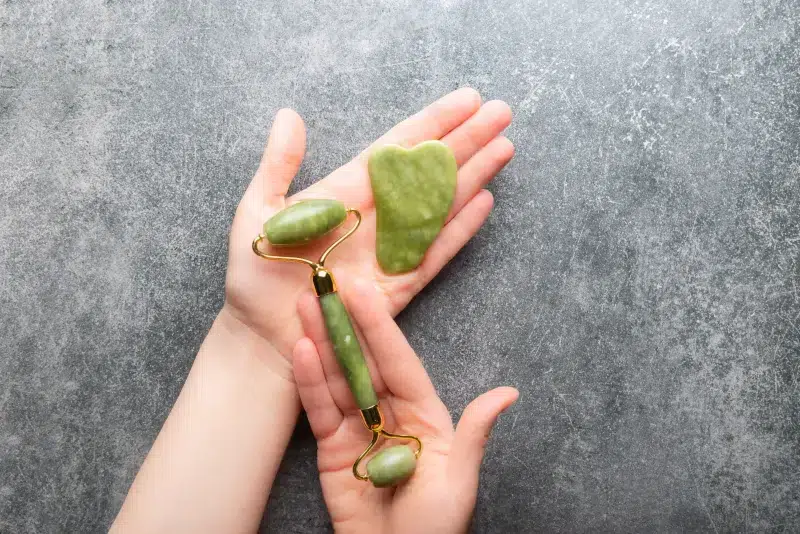 Jade roller and gua sha in a woman’s hands