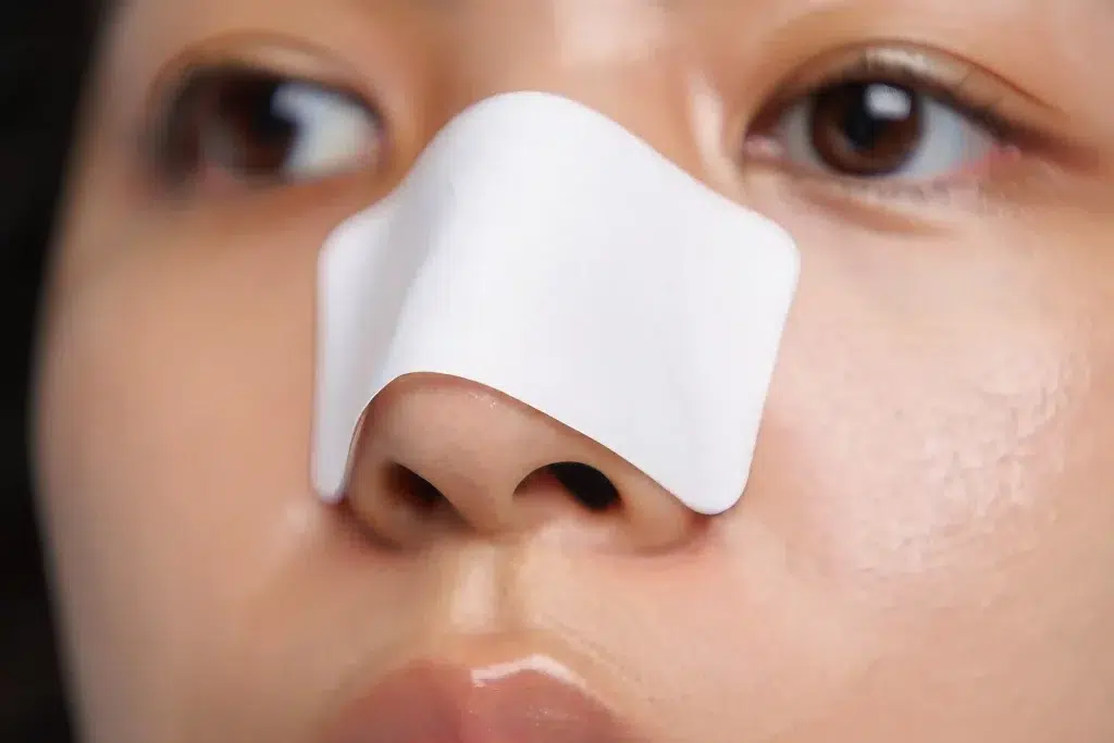Woman wearing a nose strip for blackhead extraction.
