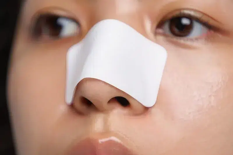 Woman wearing a nose strip for blackhead extraction.
