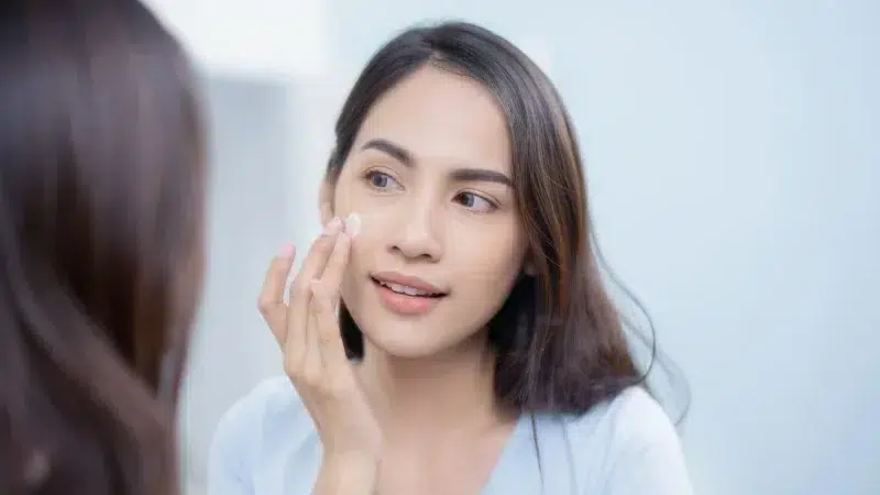 A woman applying retinol moisturiser on her face.